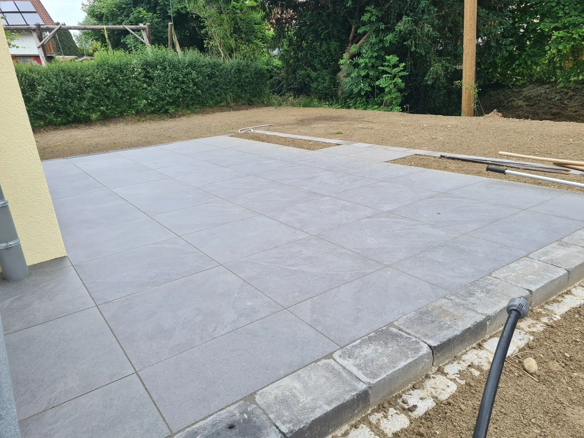 Neue Terrasse mit grauen Bodenplatten Gartenneuanlage mit moderner Terrasse aus grauen Bodenplatten