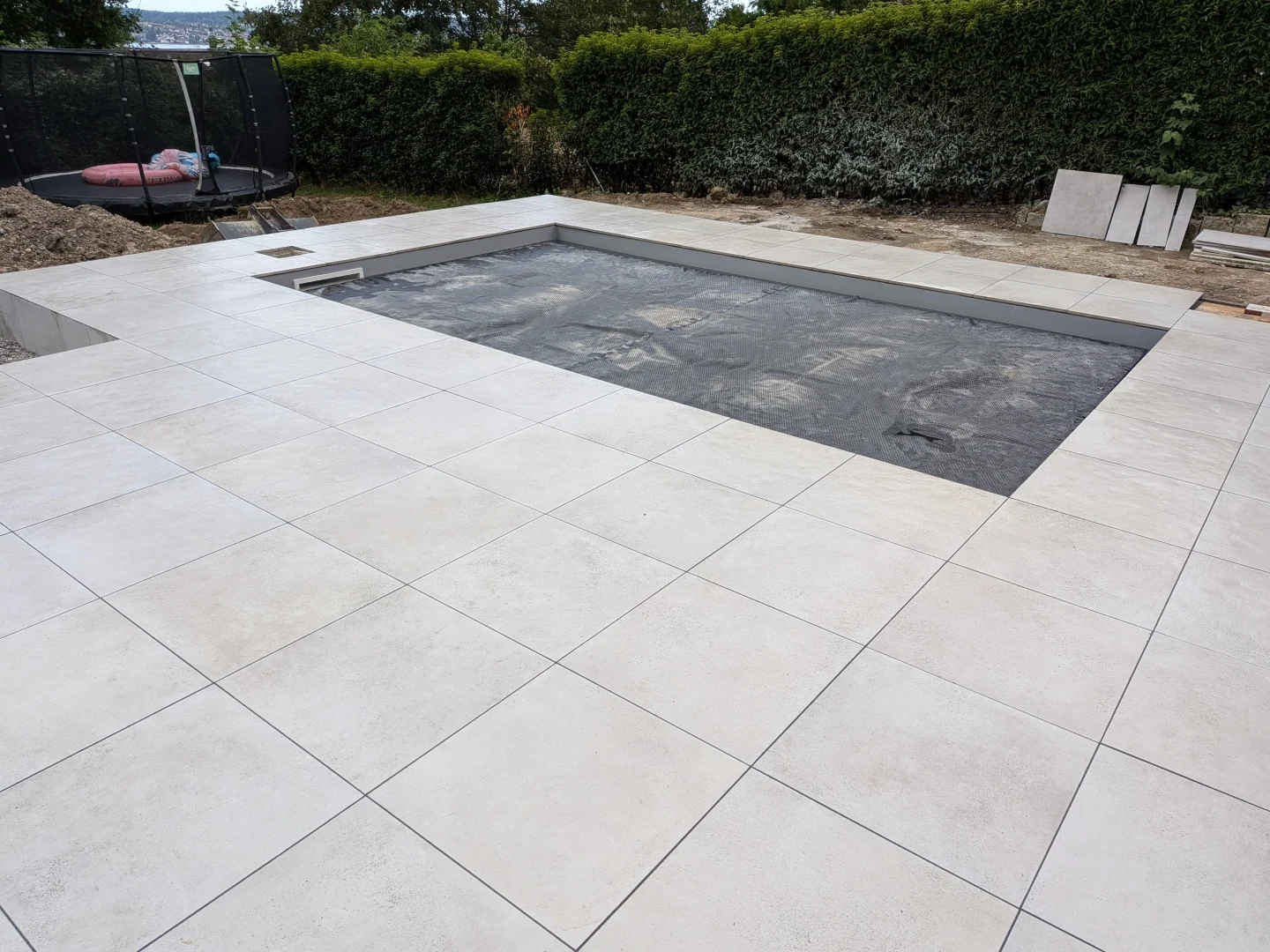 Vorbereitete Gartenfläche mit moderner Terrasse und Poolbereich nach fachgerechten Erdarbeiten
