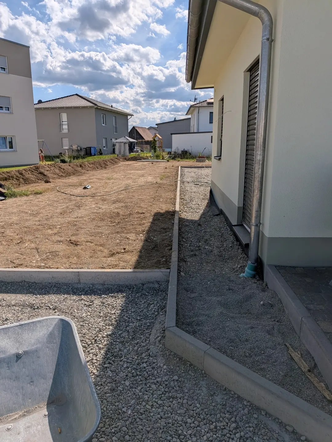 Erdarbeiten zur Trennung von Gartenfläche und Hausumrandung als Vorbereitung für Außenanlagen